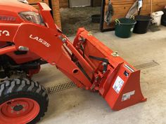 an orange tractor is parked in a garage