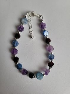 This bracelet features small flat and round coin-shaped gemstone beads. The gemstones are Amethyst (purple), Garnet (red) and Kyanite (blue). In-between each gemstone are small round sterling silver beads. It has a 1" sterling silver beaded extension and lobster claw clasp.  Custom Orders are always welcome! Most bracelets can be sized for free upon request. Adjustable Faceted Round Crystal Bracelet, Adjustable Faceted Crystal Bracelet, Adjustable Faceted Bracelet, Adjustable Round Faceted Bracelet, Adjustable Round Crystal Bracelet With Polished Beads, Handmade Blue Amethyst Bracelets, Blue Amethyst Beaded Bracelets For Gift, Blue Amethyst Beaded Bracelets As Gift, Faceted Round Purple Gemstones