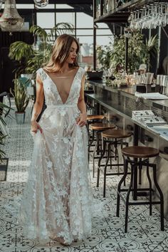 a woman standing in front of a bar wearing a white dress