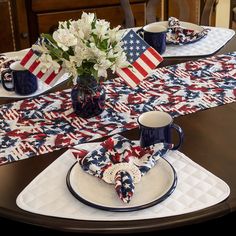 a patriotic table setting with napkins, cups and flowers on the placemats