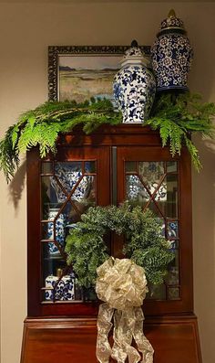 a christmas wreath on top of a china cabinet