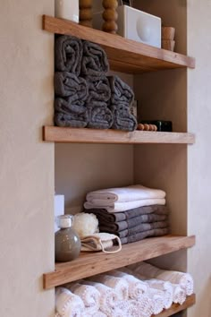 towels are stacked on wooden shelves in the bathroom