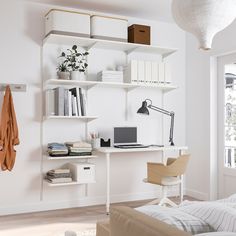 a white desk with a laptop computer on top of it and bookshelves in the background