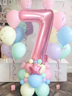 the number seven balloon decoration is pink, blue and white with stars on it's sides