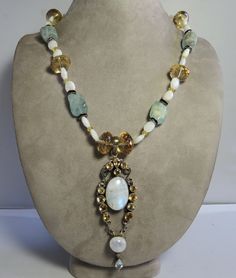 Here's a wonderful gemstone necklace with a bezel set citrine and feldspar pendant.  Links on the chain are separated with rhinestone spacers and clasp is toggle bar and ring.  It measures 20" long, and the front pendant drop is 4". Exceptional piece in completely original condition. Please see the picture with a coin for size comparison, as items may appear larger than they actually are. This is necessary to provide accurate details. Thanks for looking. And thank you for shopping sustainably. Vintage White Gemstone Necklaces, Vintage White Gemstone Necklace, White Vintage Gemstone Necklace, Unique Faceted White Jewelry, Unique White Faceted Jewelry, Unique White Jewelry With Gemstone Accents, White Oval Necklaces With Stones, White Bohemian Multi-stone Jewelry, White Oval Gemstone Beads Necklaces