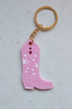 a pink cowboy boot shaped keychain with stars on the side and a gold ring