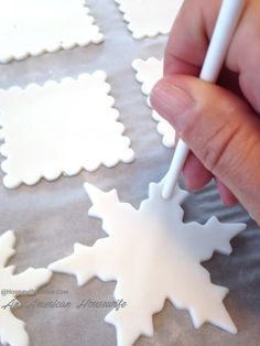 someone is decorating snowflakes with white icing