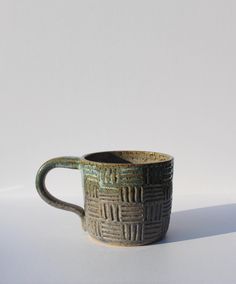 a brown and black cup sitting on top of a white table