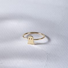 a gold ring with a small ghost face on it's side, sitting on a white surface