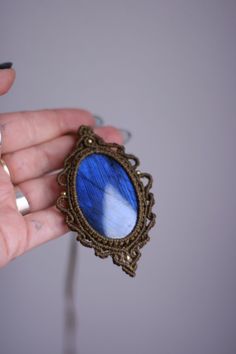 a person holding a blue and white brooch in their hand