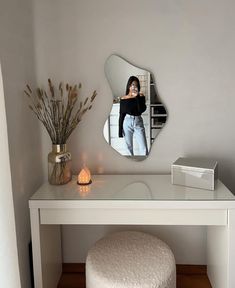 a white dressing table with a mirror on it and a stool in front of it