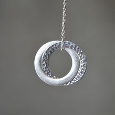 Stylish and timeless sterling silver interlocking circle pendant necklace. One ring has been hammered for a beautiful texture, and the other has been given a satin finish. The pendant hangs on a sterling silver belcher chain. Dimensions: Circles are approximately 2.5 cm (0.9") in diameter Metal: High quality 925 Sterling Silver The necklace will come in a beautiful gift box.  * CHECK OUT MORE JEWELLERY *   www.etsy.com/shop/kailajewellery Sterling Silver Hammered Jewelry Gift, Hammered Sterling Silver Jewelry Gift, Hammered Sterling Silver Jewelry For Gifts, Modern Twist Sterling Silver Necklace In Silver, Modern Twist Sterling Silver Necklace, Modern Twist Silver Sterling Silver Necklace, Modern Silver Pendant Jewelry, Sterling Silver Hammered Necklaces For Anniversary, Sterling Silver Hammered Necklace For Anniversary