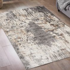 a large rug with an abstract design in grey, beige and white colors on a wooden floor