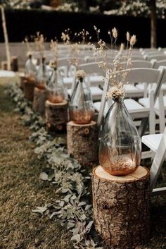 the chairs are lined up with vases filled with flowers and greenery on them