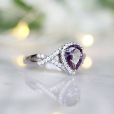 Beautiful Twisted Pear Alexandrite Ring ►Made of Sterling Silver, Rhodium Plated (S925) ►Accented with Simulated Diamonds Center Stone: Alexandrite Stone Cut: Pear Gem size: 8.0 x 6.0 mm Carat Weight: 1.25 ct. (approx.) Gemstone creation: 100% Genuine Lab-Grown Alexandrite Stone Origin: Russia Hardness: 8.5 (Mohs scale) ►Handling time: 1-2 business days ►Free domestic shipping. Usually takes 2-5 business days. ►Wrapped & ready to give in a beautiful box. Classic Amethyst Promise Ring With Center Stone, Classic Amethyst Cubic Zirconia Promise Ring, Classic Amethyst Promise Ring Round Cut, Classic Trillion Cut Jewelry With Accent Stones, Classic Amethyst Promise Ring With Halo Setting, Classic Amethyst Halo Promise Ring, Elegant Trillion Cut Birthstone Rings, Trillion Cut Center Stone Jewelry For Anniversary, Trillion Cut Halo Setting Jewelry For Anniversary