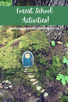 a small blue door sitting on top of a moss covered ground next to a tree