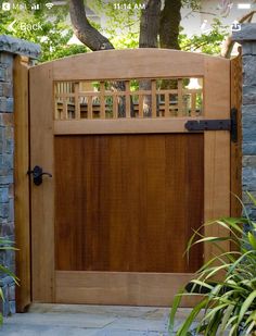 an open wooden gate in front of a tree