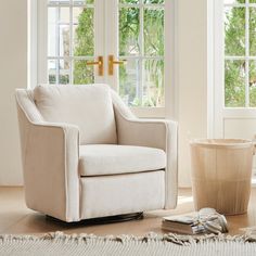 a white chair sitting in front of two windows next to a potted plant on the floor