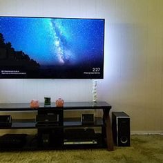 a flat screen tv sitting on top of a wooden table in front of a wall