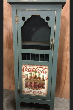 an old blue cabinet with coca cola painted on it