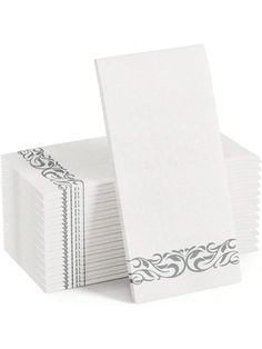 a stack of white paper napkins with silver trimming on each side and an ornate border