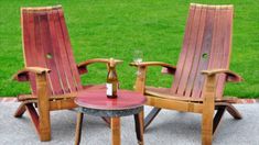 two wooden chairs sitting next to each other near a table with a bottle on it