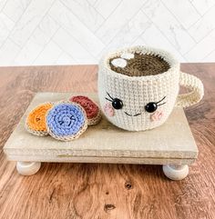 a crocheted coffee cup sitting on top of a wooden tray