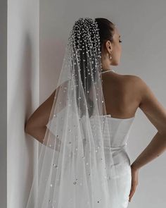 a woman wearing a wedding veil with pearls on the side and back of her head