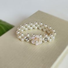 "This elegant handmade pearl bracelet would be a perfect gift for your flower girl or for a junior bridesmaid. This pearl bracelet is made with 6 mm IVORY glass pearls and crystal Toho beads and adorned  with IVORY sequin flower and rhinestones. The flower is hand beaded of ivory sequins and pearls and is app. 2 cm in diameter.    The bracelet is beaded on a stretch elastic cord.  Size: 6\" Size is fit for 4 to 8 year olds. If you would like a different size, please add it in the Note to seller Elegant Beaded Bracelets With Flower Charm As Gift, Pearl Bracelet With Pearl Charm For Bridesmaids, Pearl Beaded Bracelets With Pearl Charm For Bridesmaids, White Beaded Bracelets With Pearl Charm For Bridesmaids, Handmade Adjustable Pearl Bracelet For Wedding, Adjustable Pearl Charm Bracelet For Bridesmaids, Adjustable Pearl Bracelets For Bridesmaids, Adjustable Pearl Bracelet For Bridesmaids, White Dainty Pearl Bracelet With Flower Shape