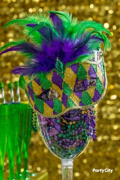 a purple and green mardi gras mask on top of a goblet