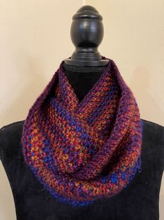 a multicolored knitted cowl on top of a black mannequin