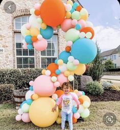 a little boy standing in front of a bunch of balloons