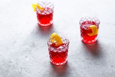 three glasses filled with red liquid and lemon wedges