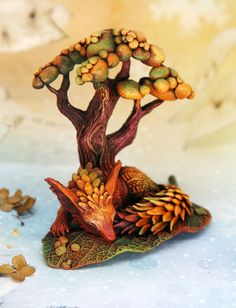 a small figurine of a tree on top of a leaf covered ground with butterflies around it