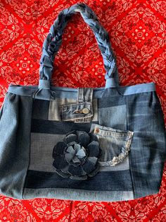 a denim purse with a flower on the front and side pocket, sitting on a red background