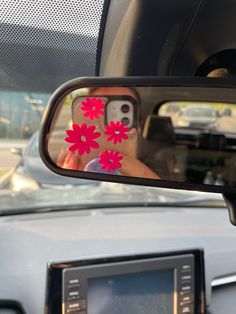 a person taking a photo in the rear view mirror of a car with red flowers on it