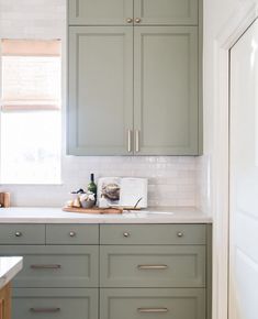 a kitchen with green cabinets and white counter tops