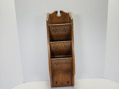 an old wooden book shelf with three drawers on it's sides, against a white wall