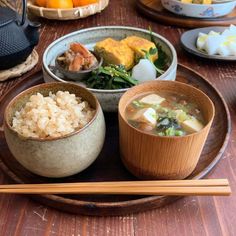 a wooden table topped with bowls of food and chopsticks on top of it