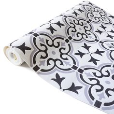 a black and white wallpaper with an ornate design on it's side, next to a roll of toilet paper