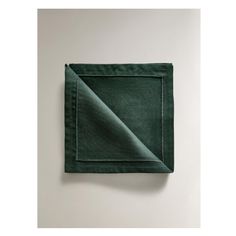 a green napkin folded on top of a white wall with a square in the middle