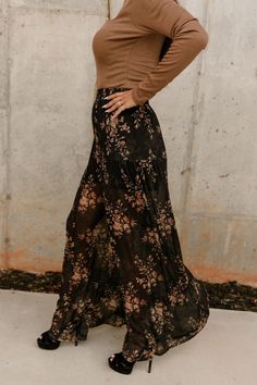 The Alaiya Black & Rust Floral Flare Pants combine elegance with a bold floral statement. Featuring black sheer fabric adorned with a striking rust floral print, these pants offer a flowy silhouette with wide pant legs. The black shorts lining ensures coverage, while the elastic waistband provides a comfortable fit. Perfect for making a style statement, the Alaiya pants blend fashion-forward design with effortless comfort. Bohemian Maxi Bottoms With Floral Print, Bohemian Maxi Length Bottoms With Floral Print, Bohemian Maxi Length Floral Print Bottoms, Bohemian Black Pants, Bohemian Style Flowy Bottoms With Floral Print, Bohemian Flowy Bottoms With Floral Print, Flowy Bohemian Bottoms With Floral Print, Black Sheer Flowy Skirt, Chic Sheer Bottoms For Fall