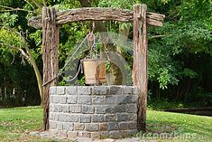 an outdoor fire pit with a potted plant on it and a wooden arbor in the background