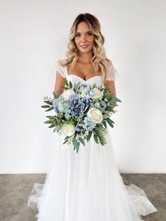 a woman in a white wedding dress holding a blue and white bridals bouquet