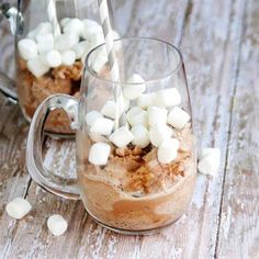 two mugs filled with hot chocolate and marshmallows on a wooden table