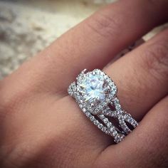 a woman's hand with a diamond ring on top of her wedding band and an engagement