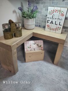 a wooden bench with two small boxes underneath it and a potted plant next to it