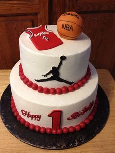 a three tiered cake with a basketball and jersey on the top, sitting on a table