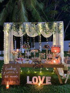 a table with candles and decorations on it in the middle of a lawn at night