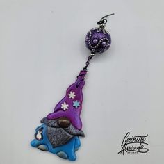 a purple and blue keychain with a gnome hat on it's side